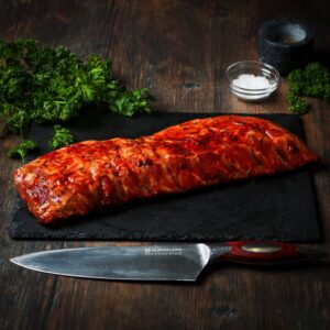 Stunning rack of ribs displayed on a wooden board next to a knife.