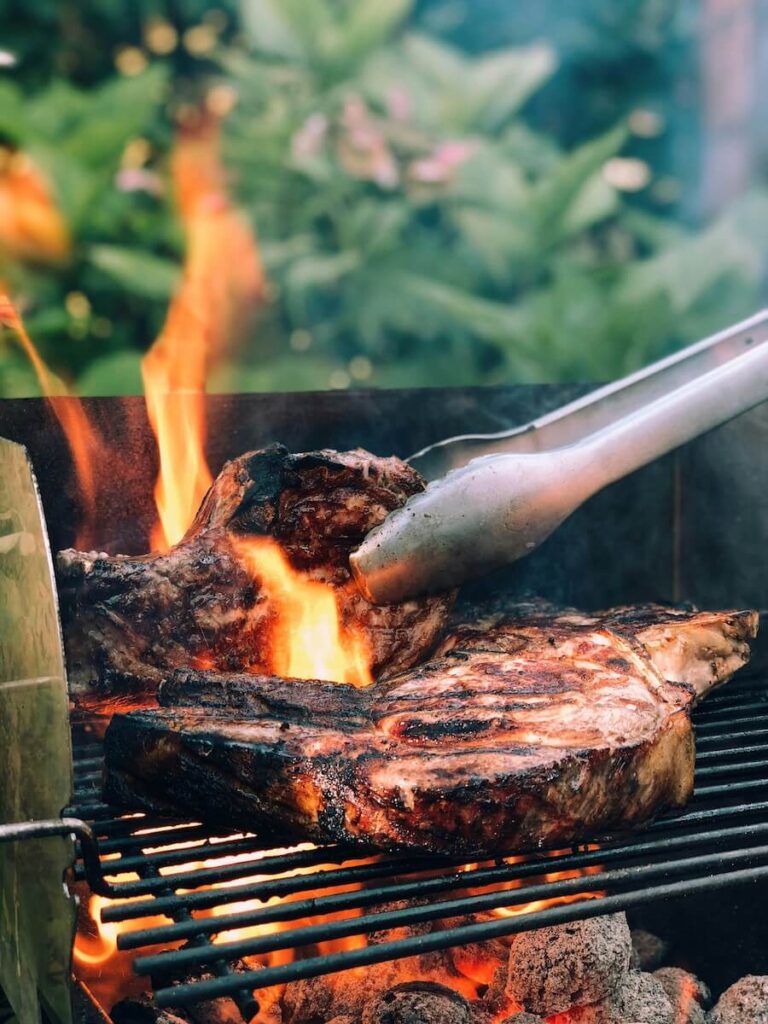 Barbecue tongs turning meat on a bbq