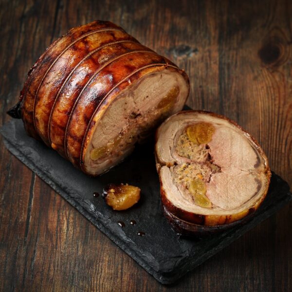 Stuffed lamb saddle displayed on a black stone board, sliced to reveal the filling