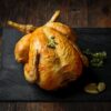 Golden, crispy fried whole chicken placed on a black stone board